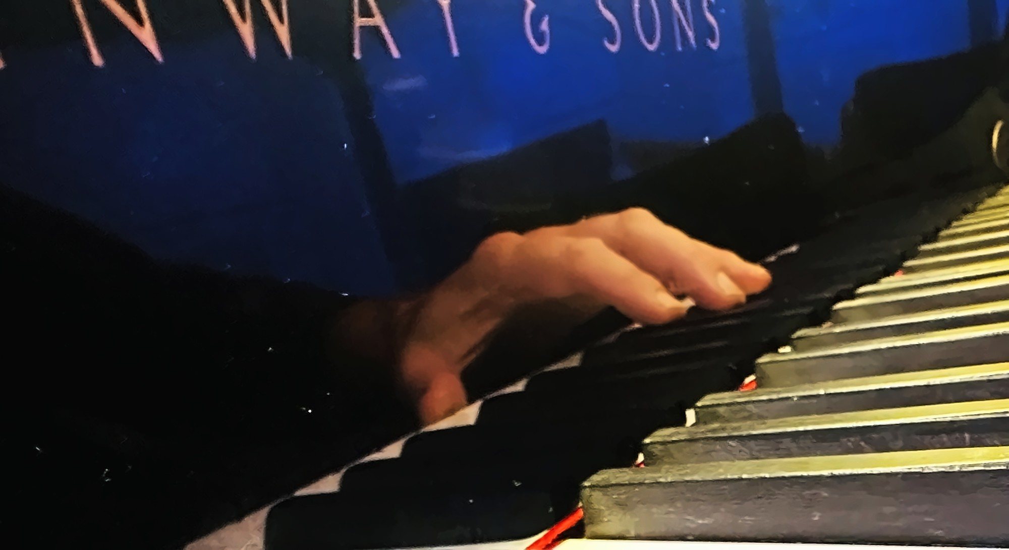 His hand on the keys of the Steinway